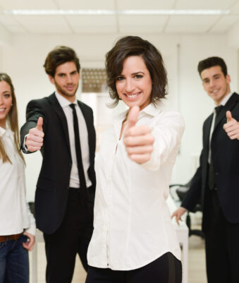 Portrait of cheerful businessteam giving thumbs up with a young woman as leader